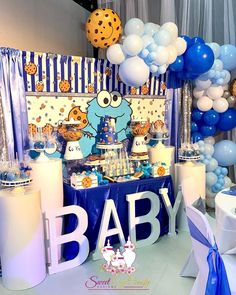 a baby shower party with blue and white decorations, balloons, and other items on the table