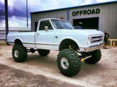 a large white truck parked in front of a building with big tires on it's tires