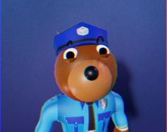 a teddy bear wearing a blue shirt and tie standing next to a purple wall with a pink border