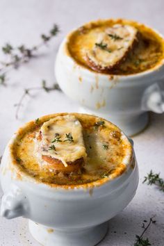 two white bowls filled with food sitting on top of a table next to each other