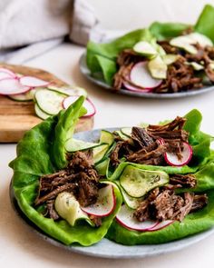 two plates filled with lettuce topped with meat and radishes next to a cutting board