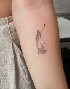 a woman's arm with a small fish tattoo on the left side of her arm