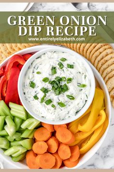 a white bowl filled with dip surrounded by veggies and crackers on the side