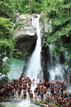 a group of people standing in front of a waterfall with water falling down it's sides