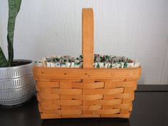 a basket with cloths in it sitting on a table next to a potted plant