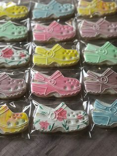 many decorated cookies are in plastic bags on the table, some have bows and shoes