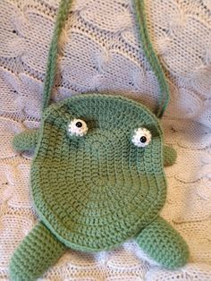 a crocheted green bag with two eyes on it