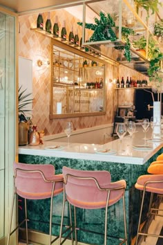 the bar is decorated with pink velvet chairs and gold trimmings, along with green marble countertops