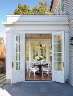 an open patio door leading to a dining room with white chairs and table on it