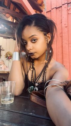 a woman with dreadlocks sitting at a table next to a glass of water