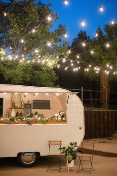 an old trailer converted into a mobile home with lights strung over the roof and windows