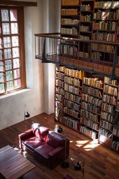 a living room filled with lots of books on top of a wooden floor next to a window