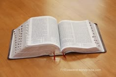 an open book sitting on top of a wooden table next to a red string and pen