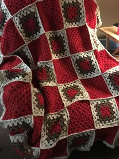 a red and white crocheted blanket sitting on top of a chair