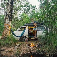 two people standing on the back of a van with a hammock hanging from it's roof