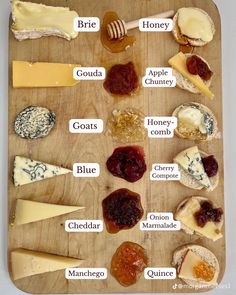 a wooden cutting board topped with lots of different types of cheeses and jams