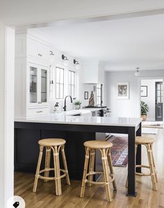 a kitchen with two stools next to an island in the middle of the room