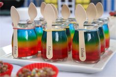 colorful desserts with wooden spoons in them on a tray at a birthday party