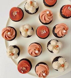 cupcakes with pink and white frosting are arranged on a plate, ready to be eaten