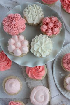 several cupcakes on plates with pink and white frosting in the shape of flowers