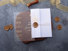 the wedding stationery is laid out on top of some coins and paper with gold foil