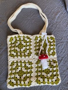 a crocheted bag sitting on top of a bed covered in green and white material