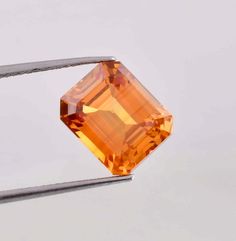 an orange diamond is being held by two tongs