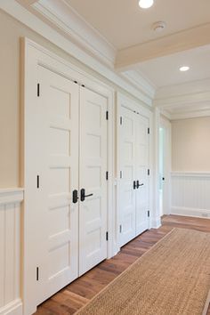 there are many doors in this room with wood flooring and white paint on the walls