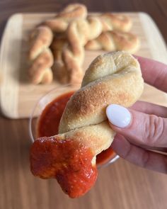 a person is holding a piece of bread in their hand and dipping sauce on the other side