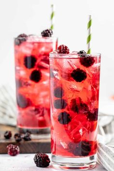 two glasses filled with raspberry lemonade soda and topped with fresh blackberries