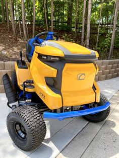 a yellow lawn mower sitting on top of a sidewalk