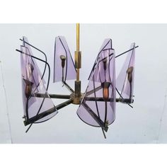 a chandelier with purple glass shades hanging from it's metal frame and gold accents