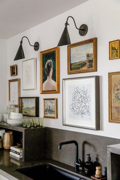 a kitchen with pictures hanging on the wall and a sink in front of an oven