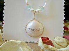 a necklace with a shell and pearls hanging from it