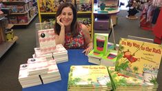 a woman sitting at a table with many books in front of her and talking on the phone