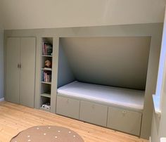 there is a bed in the corner of this room with built - in bookshelves