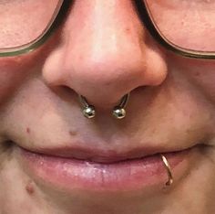 a close up of a person wearing glasses and nose rings with piercings on them