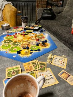 a coffee cup sitting on top of a table next to a game board and pieces of paper