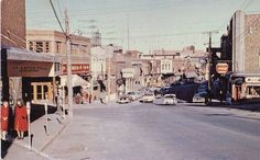 an old photo of a city street with cars parked on the side of the road