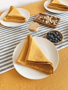 the table is set with plates, napkins and bowls of food on it's placemats