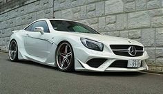 a white sports car parked in front of a brick wall with black rims on it