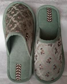 a pair of green slippers sitting on top of a bed