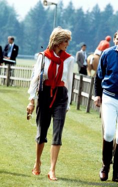 two women walking in the grass with jockeys behind them