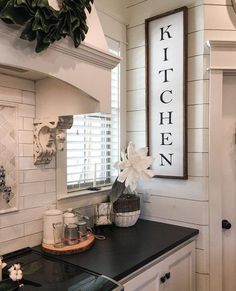 a kitchen sign hanging on the wall above a stove top oven and counter with dishes in front of it