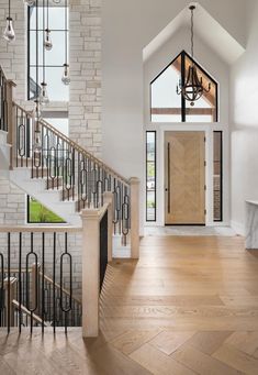 an entryway with stairs, chandelier and light wood flooring is shown