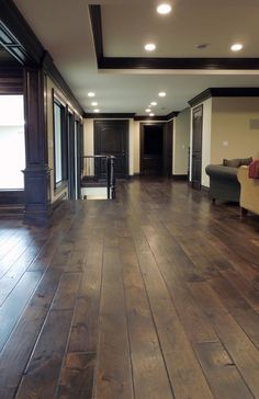 an empty living room with hard wood floors and dark wooden trimming on the walls