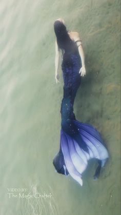 a woman is floating in the water wearing a long blue dress and holding her hand on her hip