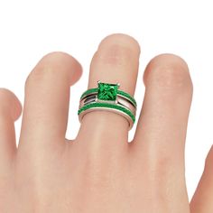 a woman's hand with a green ring on top of her finger and an emerald colored stone in the middle