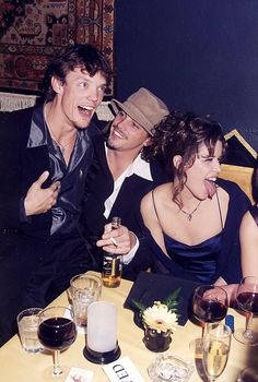 three people sitting at a table with wine glasses