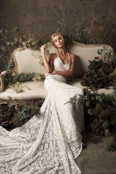 a woman sitting on top of a couch wearing a white dress and posing for the camera